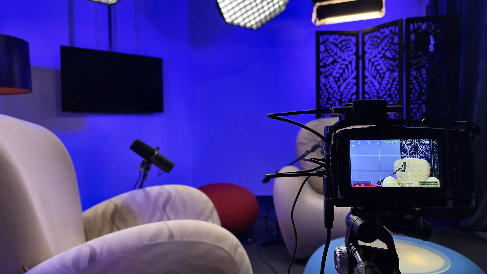 Κάμερα σε τρίποδο στο Video Podcast Studio, με την οθόνη της να δείχνει το κάδρο της πολυθρόνας και του μικροφώνου